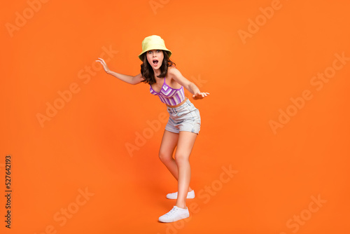 Full length photo of carefree excited woman dressed violet bra riding surf board e isolated orange color background