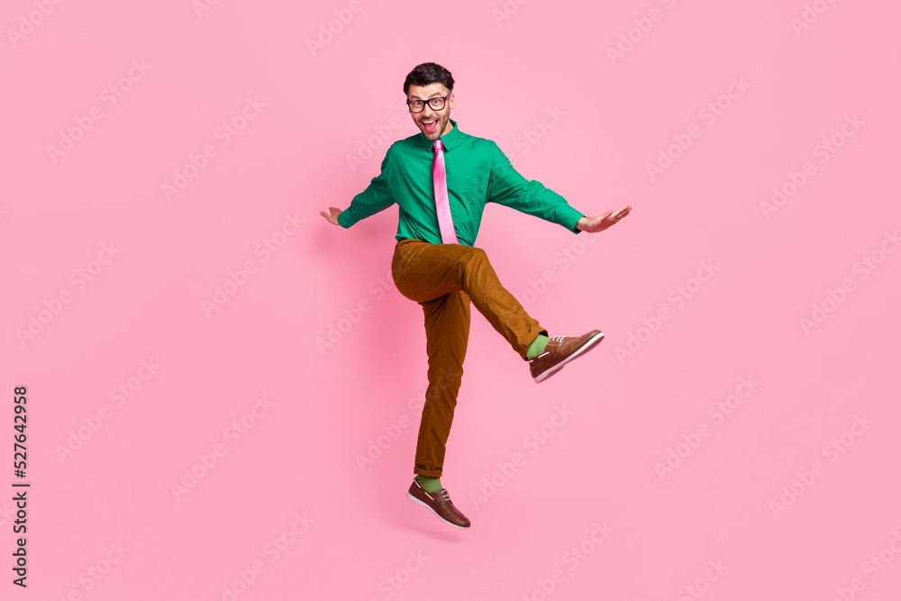 Full length photo of sweet charming guy wear green shirt spectacles jumping dancing isolated pink color background Full length photo of sweet charming guy wear green shirt spectacles jumping dancing isolated pink color background