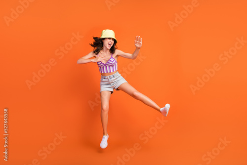 Full length photo of sexy strong woman dressed violet bra jumping up practicing karate isolated orange color background
