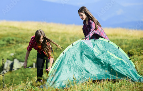 No care and no rush. mountain tourism camp. hiking outdoor adventure. family camping. reach destination place. two girls pitch tent. wanderlust discovery. friends spend free time together photo