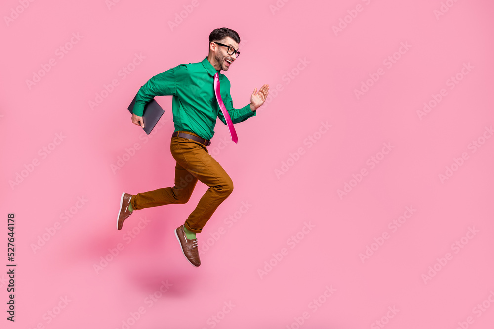 Full length photo of funky excited guy wear green shirt spectacles holding gadget jumping running empty space isolated pink color background