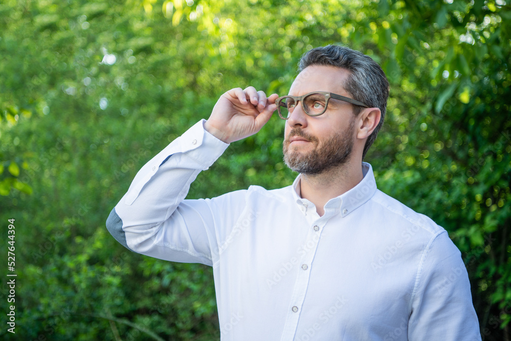 Handsome professional guy in eyeglasses looking up natural background, eyesight Handsome professional guy in eyeglasses looking up natural background, eyesight