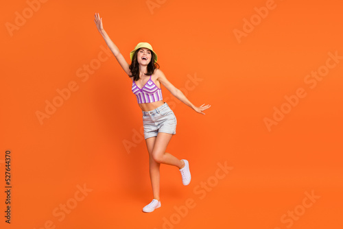 Full length photo of excited dreamy woman dressed violet bra rising arm dancing empty space isolated orange color background