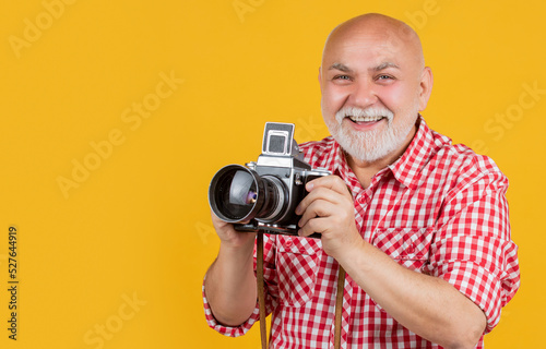 happy mature man with retro photo camera on yellow baqckground