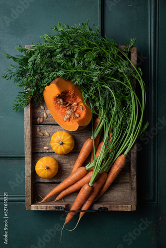 Fresh organic pumpkin and carrots with green leaves on wooden background. Vegetables. Healthy food