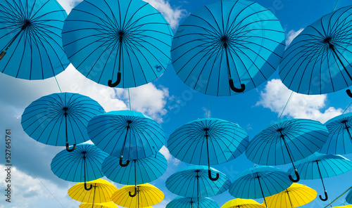 Blue and yellow umbrellas hanging bottom-up abstract sky background
