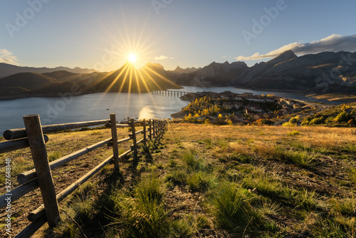 Picturesque landscape of town at riverside in mountainous valley at sunset photo