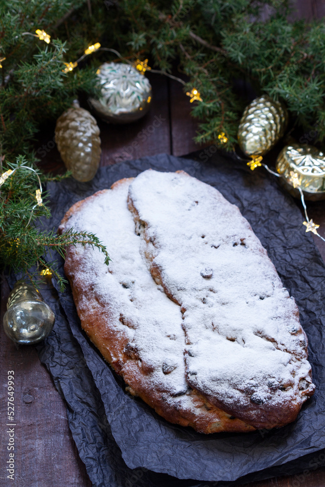 Christmas stollen with dried fruits, nuts and spices, Christmas decorations on a dark wooden background. Rustic style.