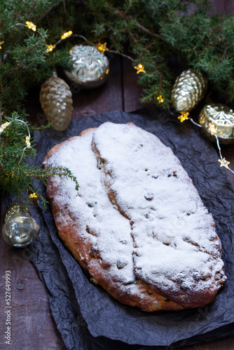 Christmas stollen with dried fruits, nuts and spices, Christmas decorations on a dark wooden background. Rustic style.