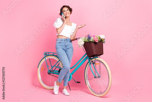 Fototapeta Naklejka Na Ścianę i Meble -  Full length photo of funky dreamy lady wear white crop top riding bike talking modern gadget isolated pink color background