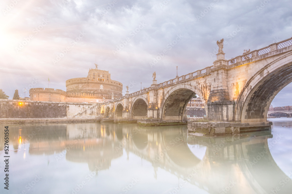 Rome capital of italy saint angelo bridge with fog sun beams and clouds