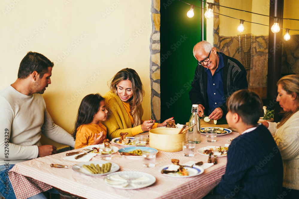 Happy latin family cooking together during dinner time at home - Focus on grandfather face