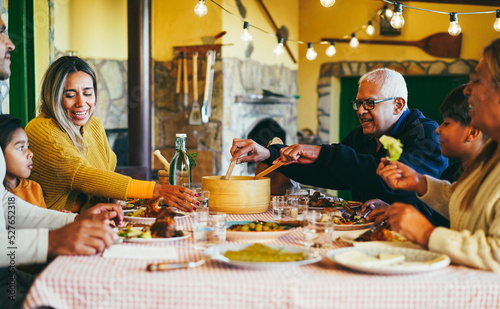 Happy latin family having fun eating together home - Focus on grandfather face