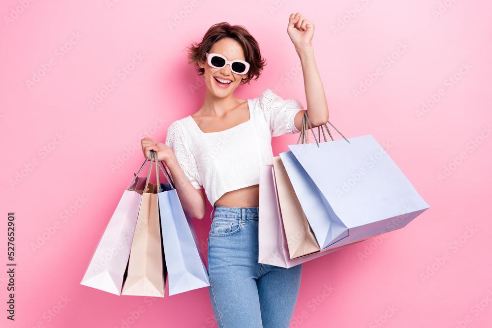 Portrait of gorgeous pretty lovely girl wear white blouse glasses raising fist up glad excited shopping isolated on pink color background