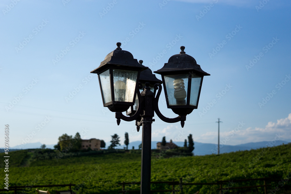 Photograph of a vintage lamppost with cloudy background and blue sky.