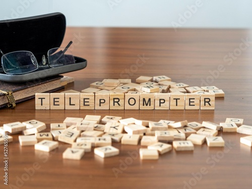 teleprompter word or concept represented by wooden letter tiles on a wooden table with glasses and a book photo