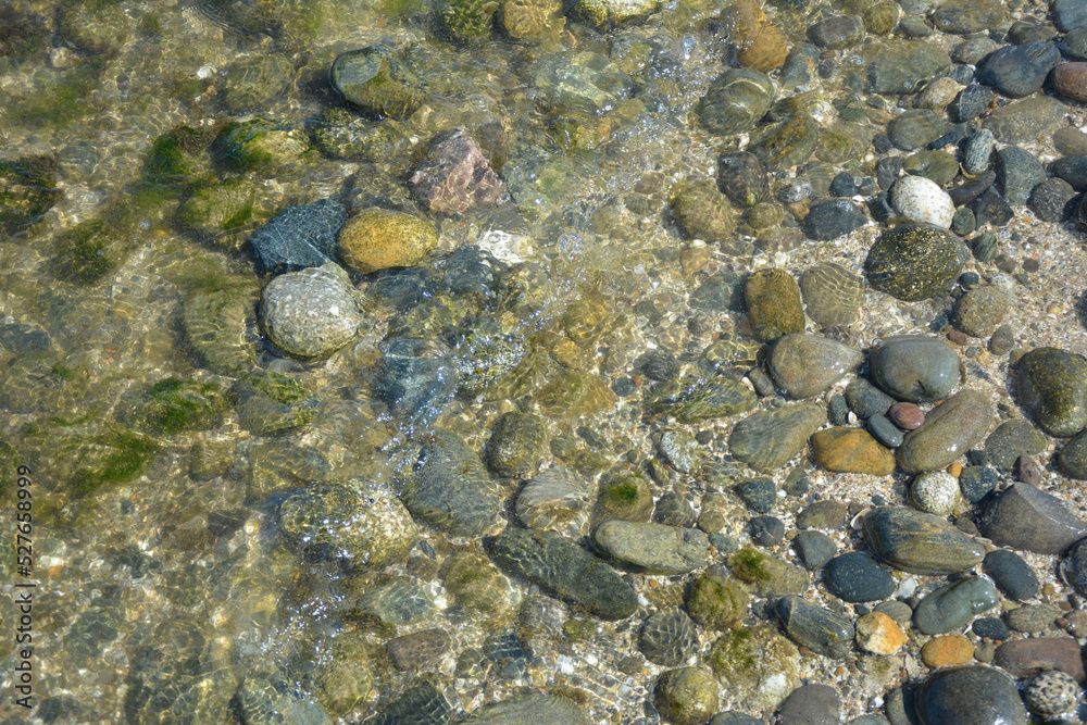 Sea pebbles in shallow water near the sea on a sunny day. Sea pebbles in shallow water near the sea on a sunny day.