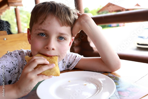 Kid eating adyghe halyuzh pie photo