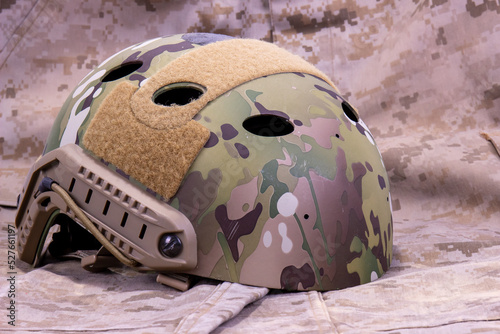 Fotografering Military Helmet On Camouflage Uniform