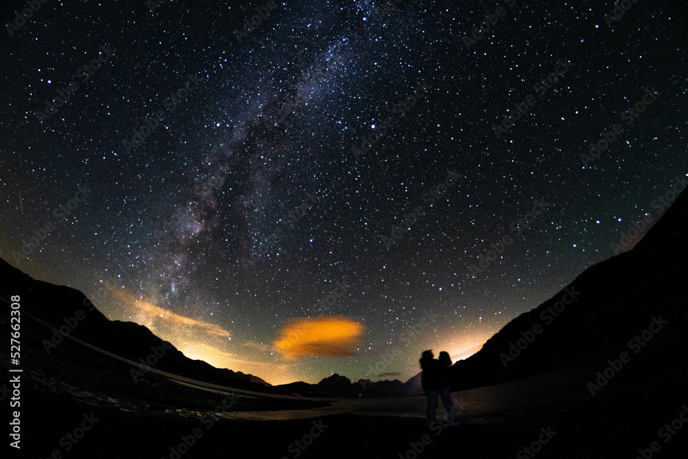 Couple under the dark sky with the Milky Way and mountains