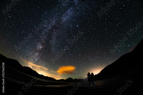 Couple under the dark sky with the Milky Way and mountains