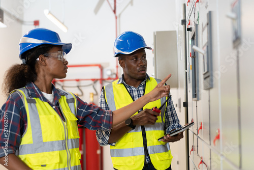 Team of electrician engineer or electronic technician maintenance electric system in control room. Group of African American electrician engineer checking electric system in control room