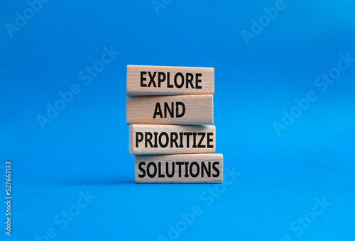 Solution symbol. Wooden blocks with words Explore and prioritize solutions. Beautiful blue background. Business and solution concept. Copy space.