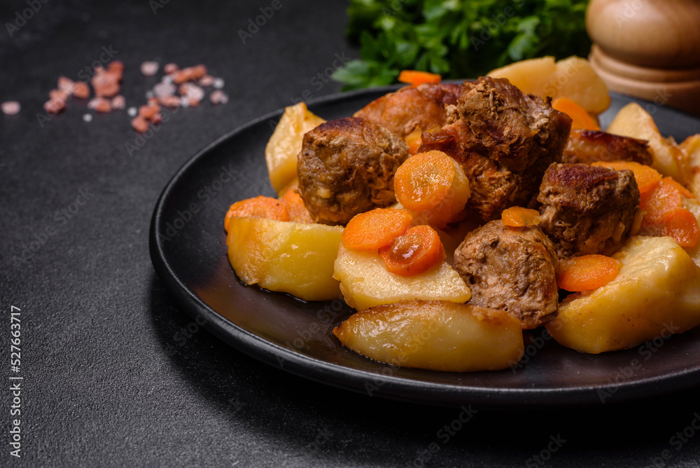 Beef meat and vegetables stew on a black plate with roasted potatoes Beef meat and vegetables stew on a black plate with roasted potatoes
