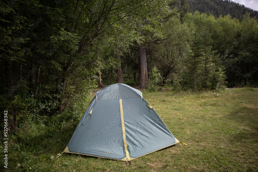 Camping in a tourist forest. A green tent set up on a picnic spot.