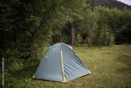 Camping in a tourist forest. A green tent set up on a picnic spot.