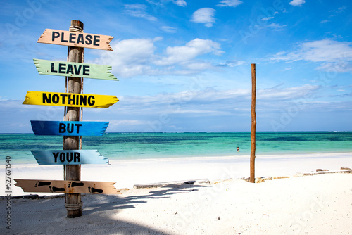 Hinweis am Strand, ein Wegweiser mit Pfeilen am einem Strand, im Hintergrund türkisfarbenes Meer und ein blauer Himmel. photo