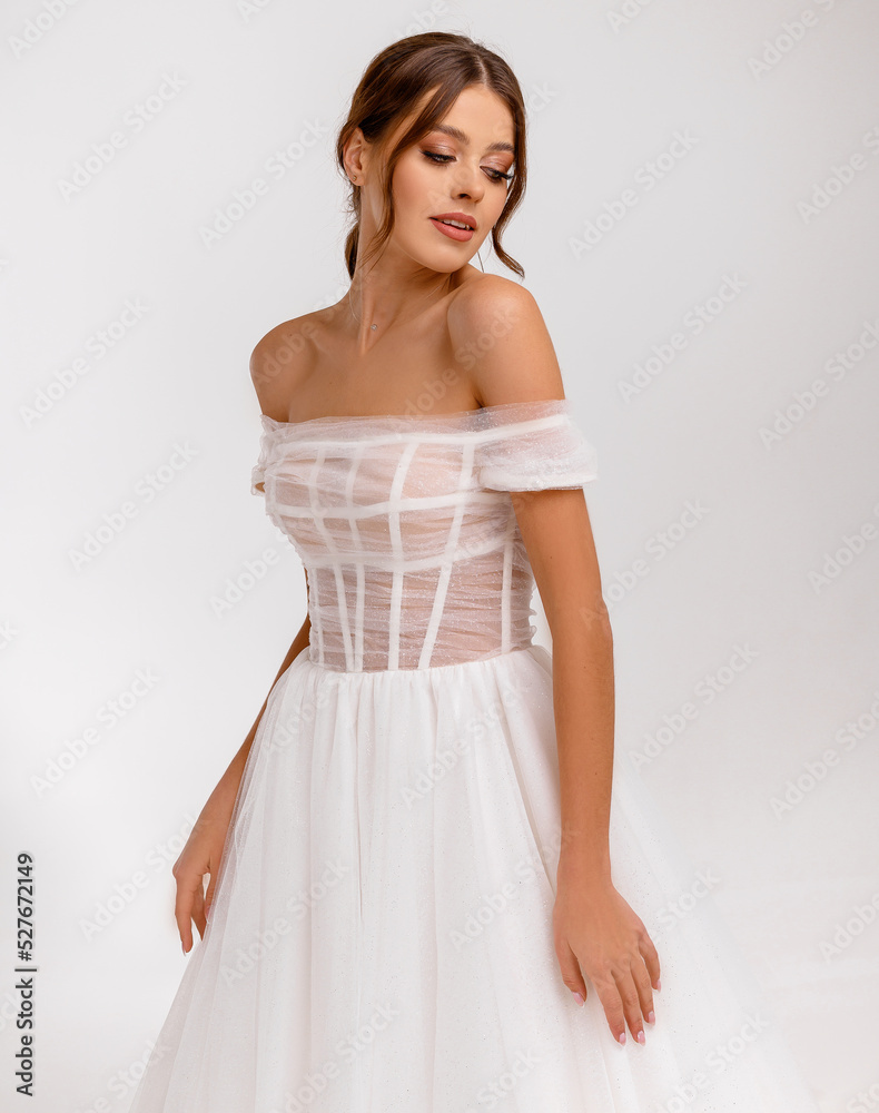 Sensual bride young woman in wedding puffy white dress with open shoulders having wedding beautiful makeup and haircut. Wedding salon studio. Elegant bride-to-be. Posing alone. Sensual bride young woman in wedding puffy white dress with open shoulders having wedding beautiful makeup and haircut. Wedding salon studio. Elegant bride-to-be. Posing alone.
