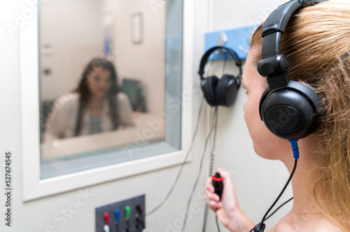 Audiologist woman doing the hearing exam to a mixed race woman patient using an audiometer in a special audio room. Audiometric testing. Hearing loss treatment. photo