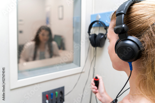 Quadro su tela Audiologist woman doing the hearing exam to a mixed race woman patient using an audiometer in a special audio room
