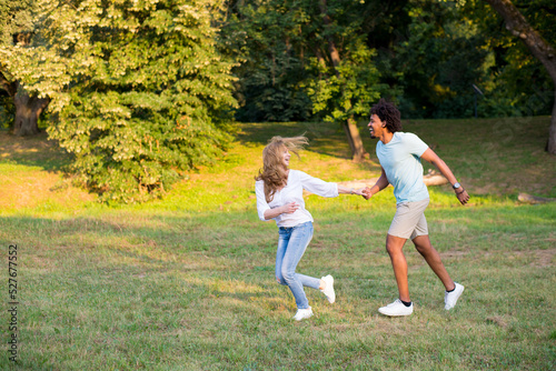 Young mixed race couple running on the summer meadow