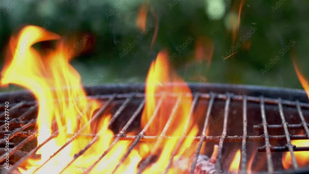 Wooden firewood and charcoal burn fire with hot orange flames, sparks and smoke in grill stove. Preparation grill for cooking outdoors on metal grate. Foreground focus. Close up. Wooden firewood and charcoal burn fire with hot orange flames, sparks and smoke in grill stove. Preparation grill for cooking outdoors on metal grate. Foreground focus. Close up.