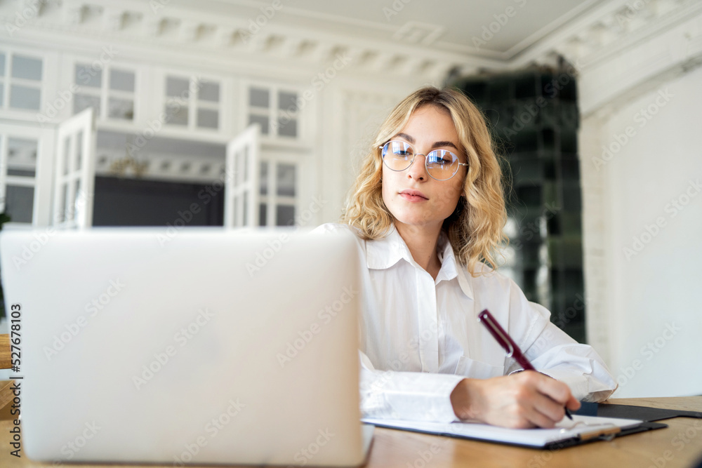 Female manager working in office online report using laptop