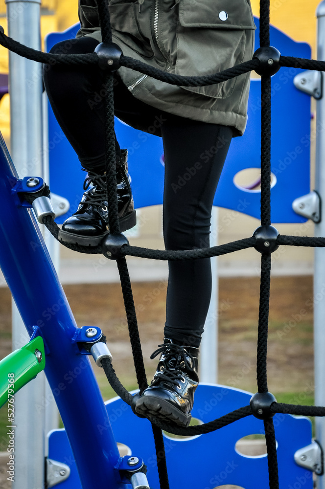 Little girl climbing up the playground equipment