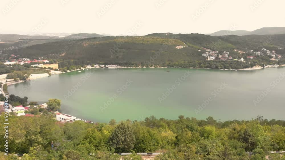 Green lake in the valley. Mountains with trees. Shooting from a drone. Small locality. Resort village. Resting-place. Vacation in the mountains. Travel and tourism. Green lake in the valley. Mountains with trees. Shooting from a drone. Small locality. Resort village. Resting-place. Vacation in the mountains. Travel and tourism.