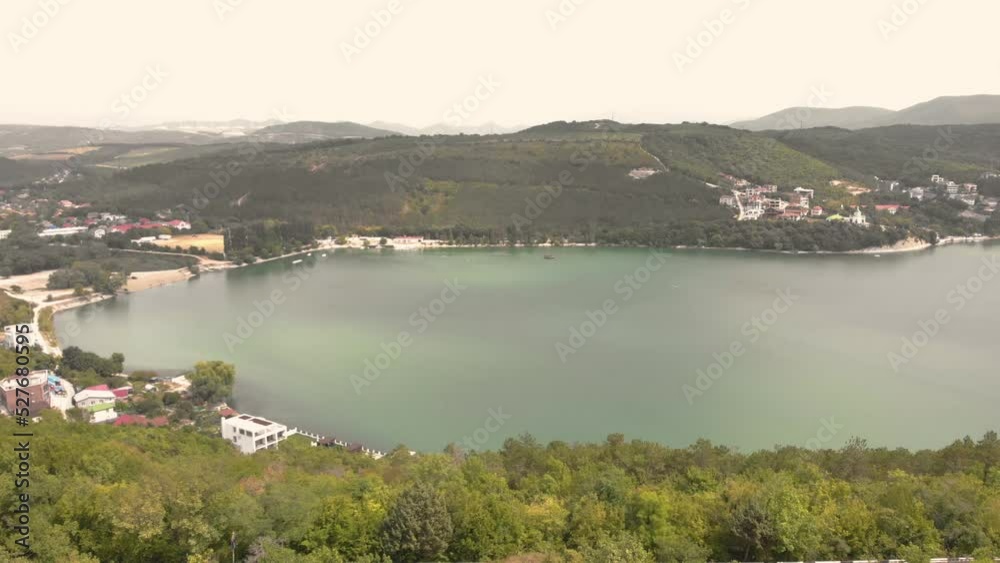 Green lake in the valley. Mountains with trees. Shooting from a drone. Small locality. Resort village. Resting-place. Vacation in the mountains. Travel and tourism. Green lake in the valley. Mountains with trees. Shooting from a drone. Small locality. Resort village. Resting-place. Vacation in the mountains. Travel and tourism.