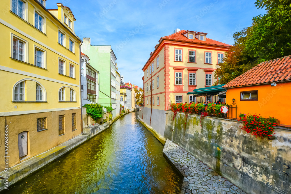 Colorful cafes, homes and buildings along the Certovka Canal as it crosses under Charles Bridge in the Old Town Lesser Quarter area of Prague, Czechia.