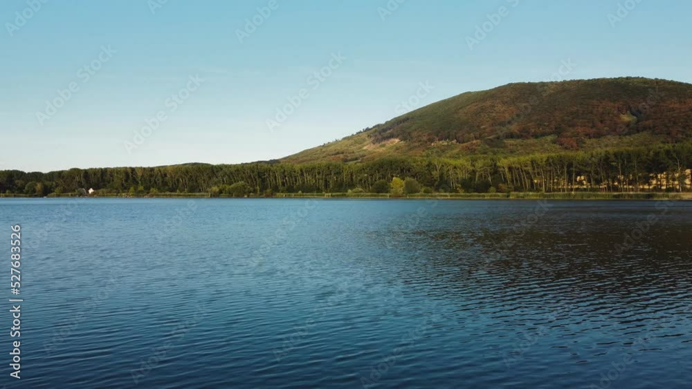 Drone flying over the peaceful and idylic blue lake on sunset. Slowly and close flight above trees and lake with perfect aerial view from drone (UAV)in Europe - Slovakia. Drone flying over the peaceful and idylic blue lake on sunset. Slowly and close flight above trees and lake with perfect aerial view from drone (UAV)in Europe - Slovakia.