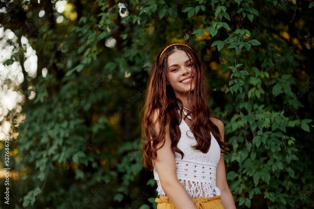 A woman in eco-friendly clothing in a hippie look dances in nature in the park and smiles at the world. The concept of harmony with the body and the surrounding nature A woman in eco-friendly clothing in a hippie look dances in nature in the park and smiles at the world. The concept of harmony with the body and the surrounding nature