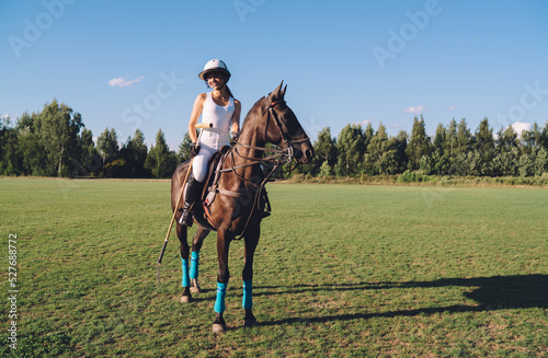 Woman riding brown horse on field