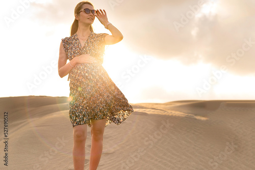 Selbstbewusste schwangere junge blonde Frau im  Kleid als Fotomodel für Beauty oder Glamour mit Babybauch in Wüste photo