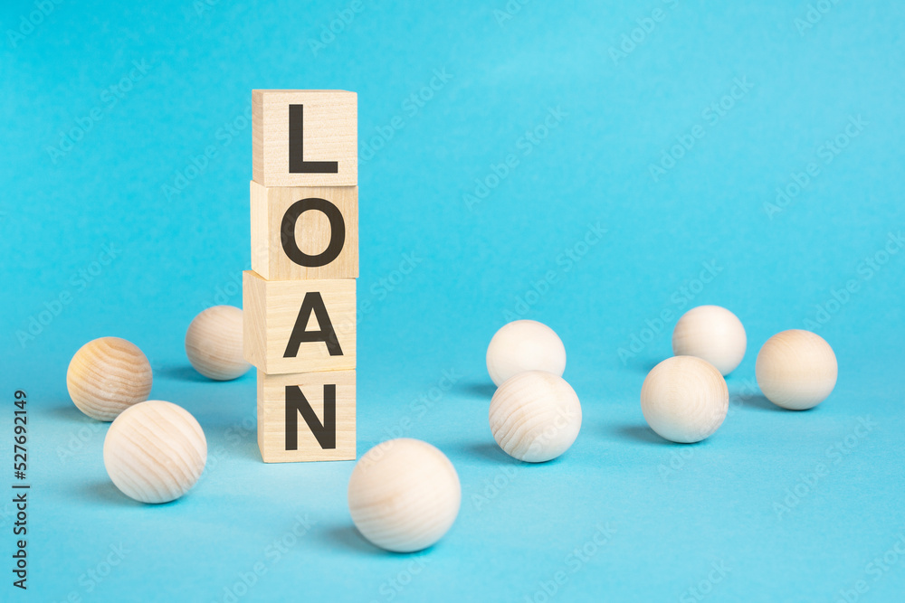 pyramid of wooden cubes with the word LOAN and wooden balls on a blue background pyramid of wooden cubes with the word LOAN and wooden balls on a blue background