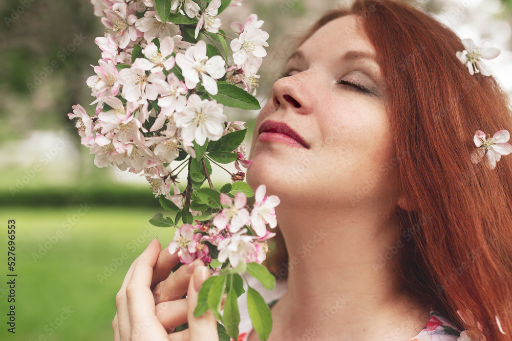 redhead young woman with closed eyes and freckles in white apple blossom redhead young woman with closed eyes and freckles in white apple blossom