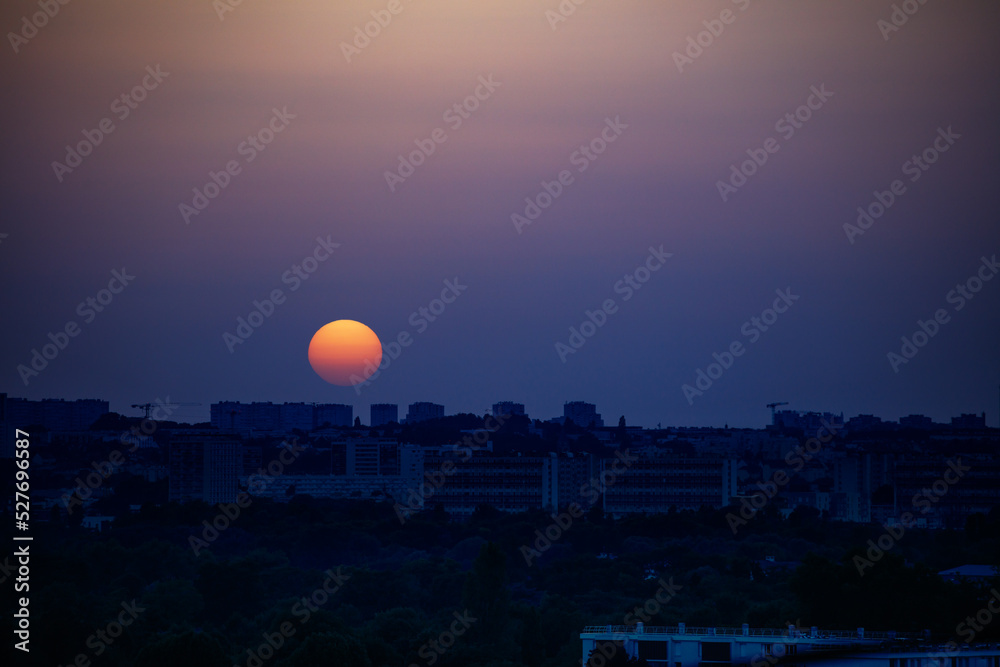 Sunset sun and town with orange disk over Paris suburb Sunset sun and town with orange disk over Paris suburb