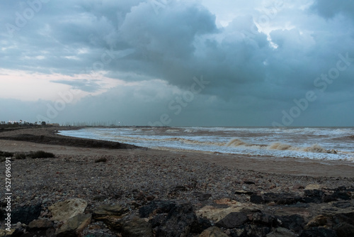 View of Sagunto beach with the rough sea with big waves after the storm under a dramatic sky. Puerto de Sagunto - Valencia
