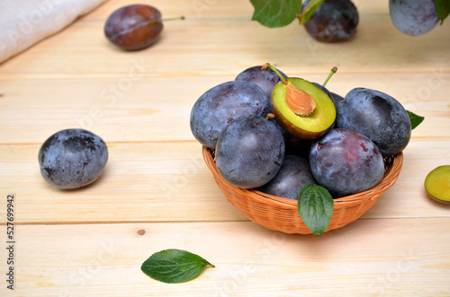 fresh plums in a basket on a wooden table